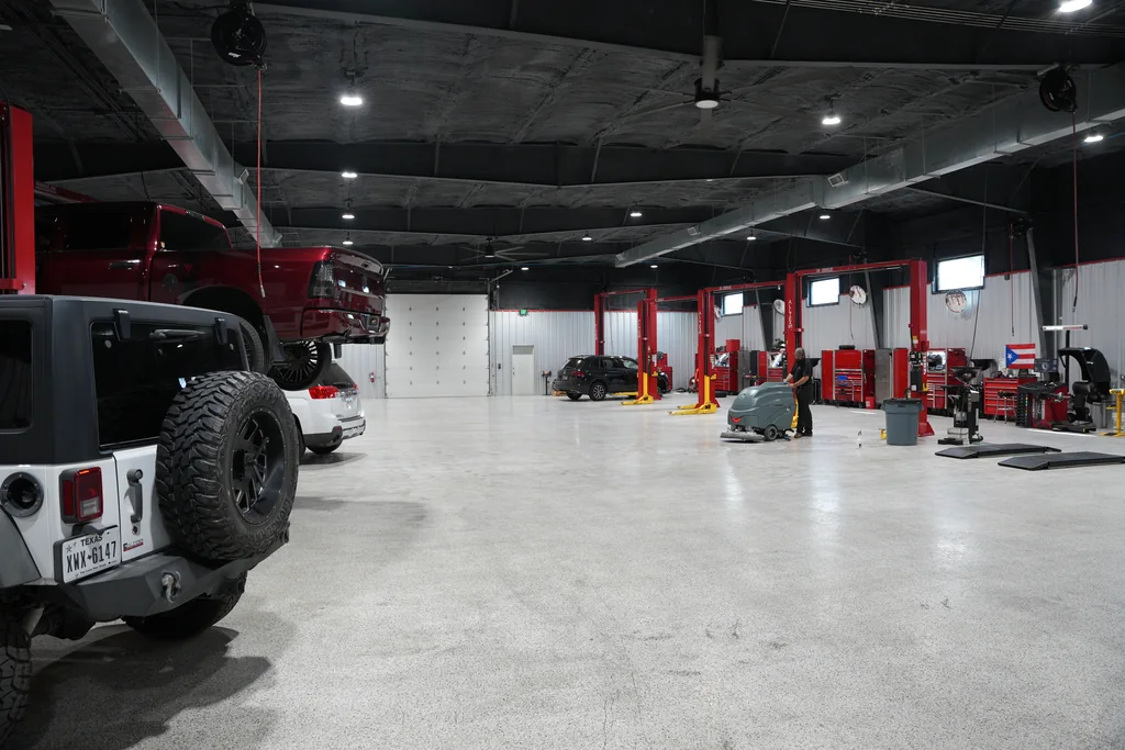 Service workshop aisle with vehicles and red lifts.