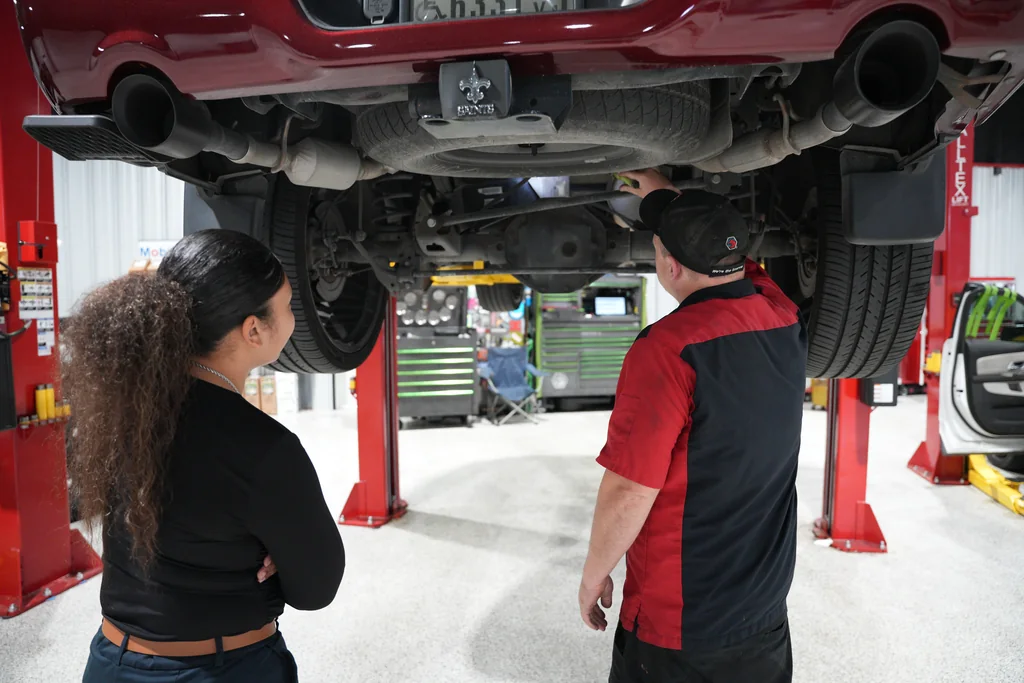 Two staff members looking underneath a raised vehicle.